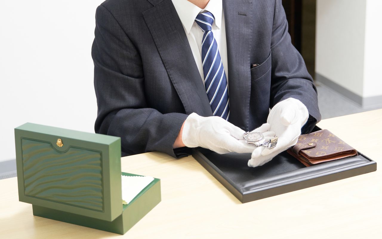 腕時計とブランド財布を査定する鑑定士の手元